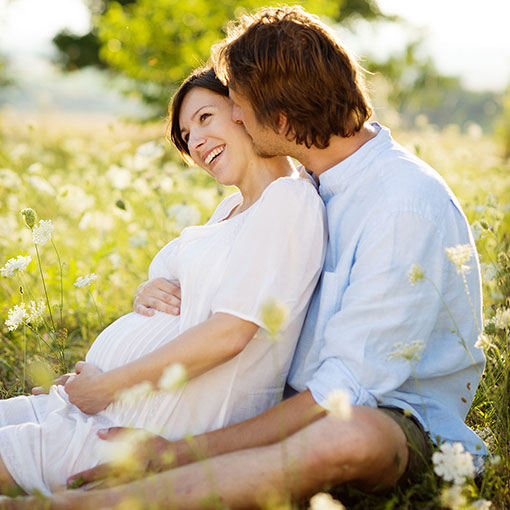 Starting a Family Expectant couple sitting in field